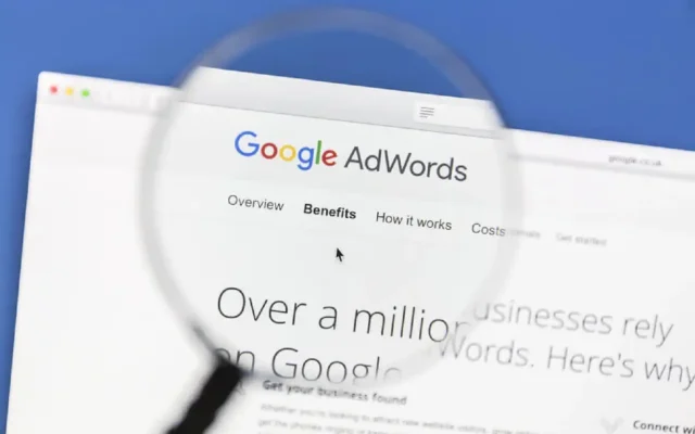 Google AdWords page under magnifying glass displaying benefits and features for businesses using agency ads accounts