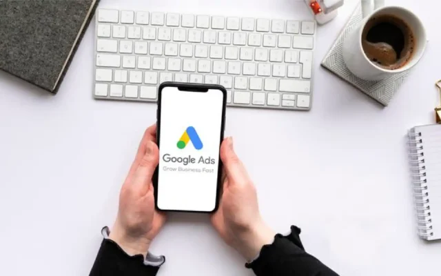 Hands holding a smartphone displaying the Google Ads app, relevant to managing a "google ads suspended circumventing systems" issue.